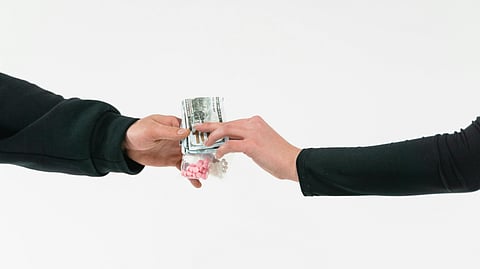 Image of 2 hands, exchanging money and drugs.