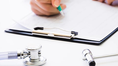 Image of a doctor writing prescription on a paper besides a stethoscope.