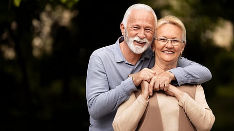 Image of an old couple hugging each other in the park.
