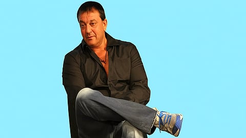 An image of Sanjay Dutt sitting in a light blue background.