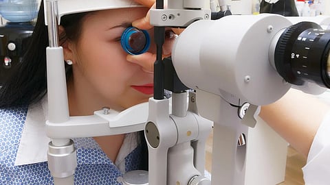 A close-up of a patient undergoing an eye examination by an ophthalmologist or optometrist using a slit lamp in a clinical setting