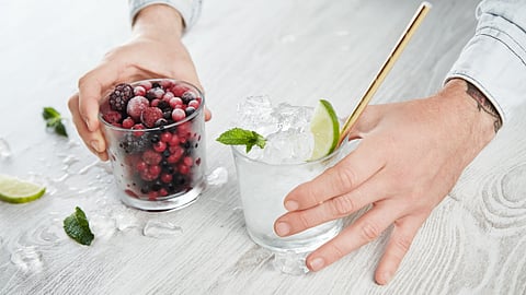 Image of berries and ice in different glasses being held by a man.
