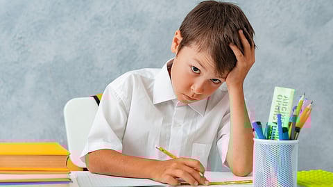 Image of child in school getting bore from the work he is doing.