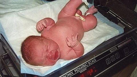 An image of a newborn overweight baby on weighing scale.