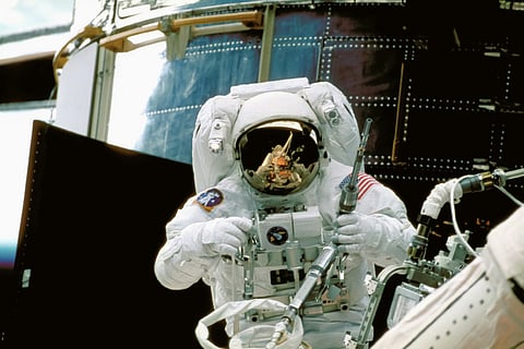 Image of a man in a space suit standing in front of a space station.