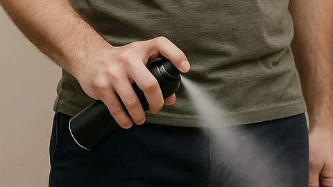 Image of a person spraying perfume in the downward direction from the bottle.