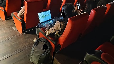A woman works on her laptop during a screening of Lokah in a Bengaluru cinema.