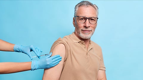 An image of a old man taking a vaccination.