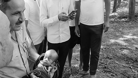 A police man holding a newborn in his hands.