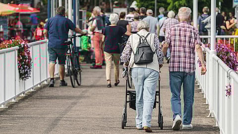 Elderly individuals walking together on a bridge, enjoying the scenery and each other's company.