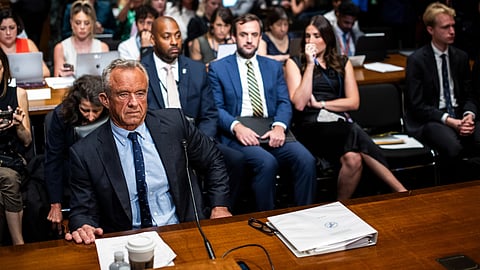 A formal meeting with people in suits seated at a conference table.