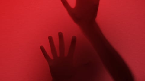 Image of hands on a red background depicting a crime scene.