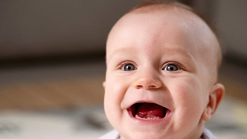 A close-up of a crawling baby with a gummy smile.