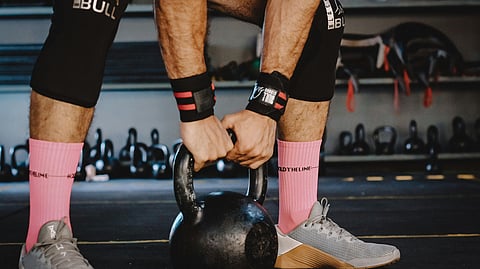 Image of a person performing kettlebell swings in a gym, demonstrating proper form and technique. 