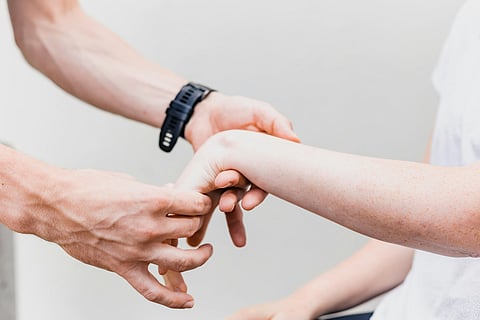 A person gently holds the wrist of another person, indicating a moment of connection or support.