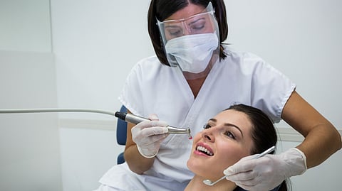 Image of a dentist working upon a patient in a clinical setting.