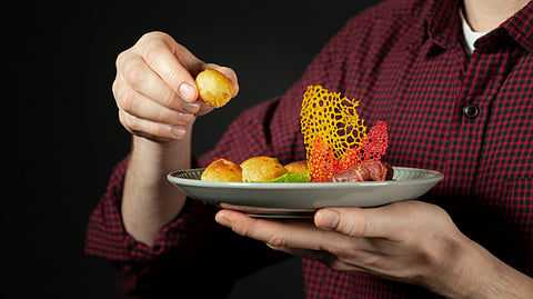A person picking up some food from a plate to eat.