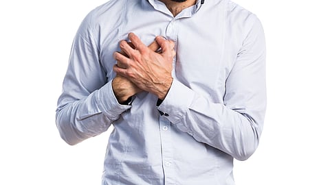 A man clutching his chest due to pain indicating a heart condition. 