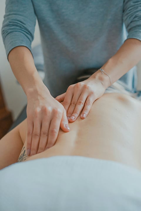 A woman receiving a back massage in a serene room, promoting relaxation and wellness.
