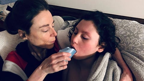 Image of a mother helping her son drink while wrapped in a blanket.