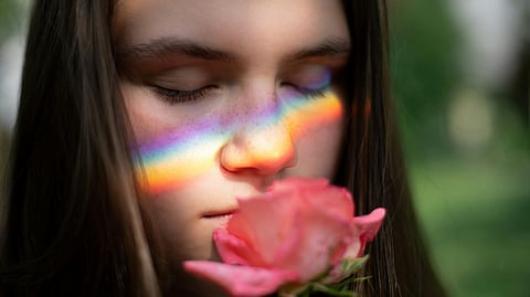 Image of a girl smelling the aroma of a flower.
