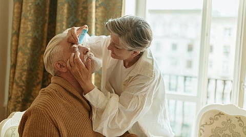 An image of a woman putting eye drops in a man's eye