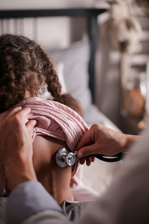 A woman uses a stethoscope to listen to a child's heartbeat during a medical examination.
