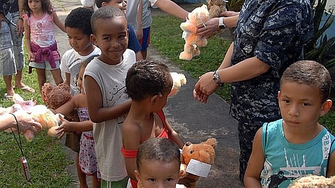 A group of children looking happy and standing with teddy bears in their hands.