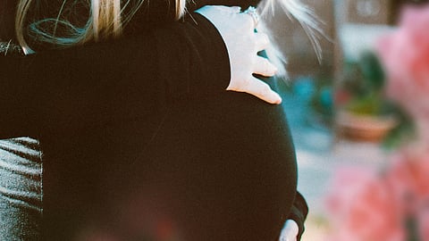 Image of a pregnant woman wearing black sweater.
