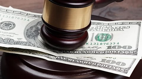 A judge's gavel rests on a stack of cash, symbolizing the intersection of law and finance.