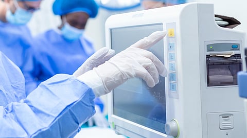 Image of a woman working on a machine in a clinical setting.