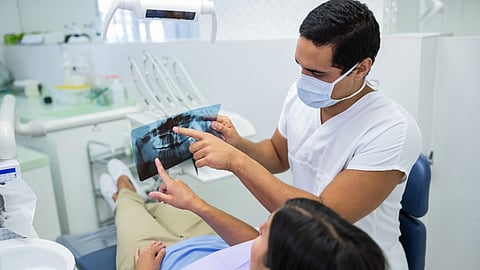 Young male dentist examining x-ray with the female patient