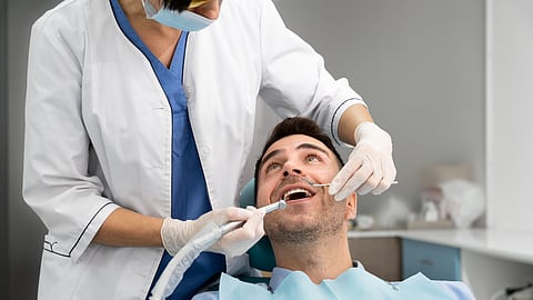 A male patient getting a dental treatment done by a dentist. 