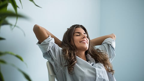 Image of a woman in blue shirt relaxing on a chair.