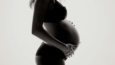 Black and white image of a pregnant woman in a bikini.