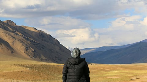 Image of a man wearing a cap and jacket in a mountainous region.