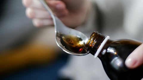 An image of cough syrup on spoon and in bottle.