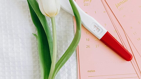Image of a flower beside a pregnancy tester over pink cards.