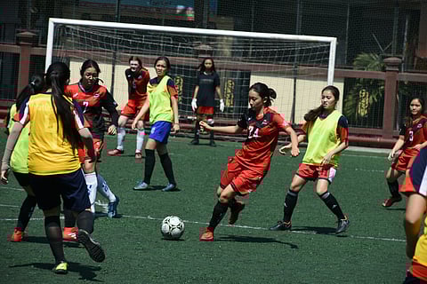 A group of girls playing soccer on a grassy field.