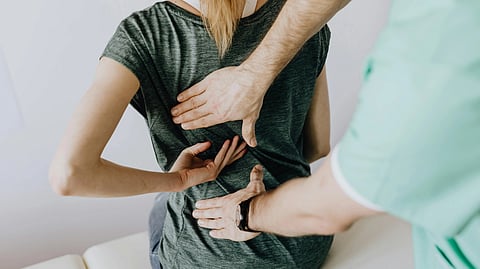 An image of patient experiencing back pain and chiropractor helping her.