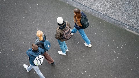Image of 4 kids going to school in winter season wearing fully covered clothes.