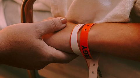 Person wearing orange and white silicone band