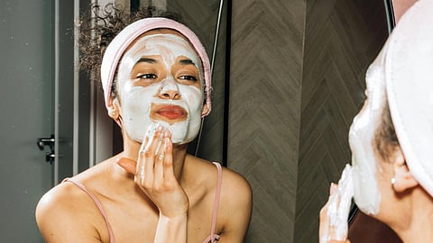 An image of a woman applying a face mask.