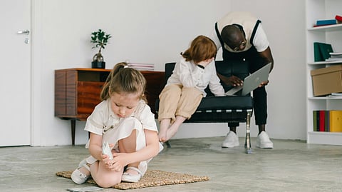 Image of a child playing and a mother taking consultation from someone in the background.