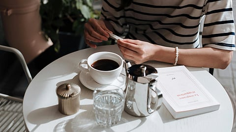 A Woman Sitting at the Table Preparing a Cup of Coffee.