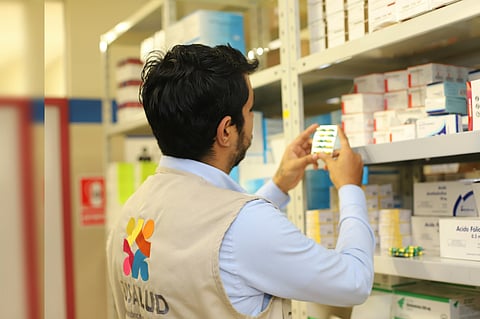 A pharmacist working on labels across medicine racks