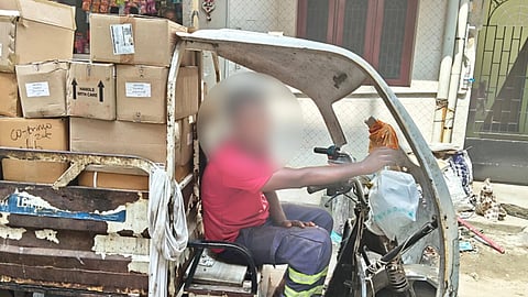 An open pickup van with many cardboard boxes stacked up and a driver on the seat with his face blurred.