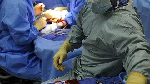 A team of medical professionals working together in a sterile operating room during a surgical procedure.