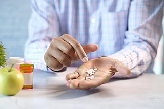 A person holding white coloured tablets in his palm.
