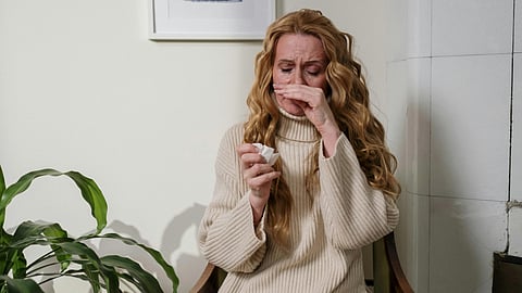 Image of a girl wearing a beige color sweater and suffering from allergies.
